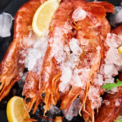 Fresh shrimps with lemon on dark background. Red raw prawns.Frozen seafood